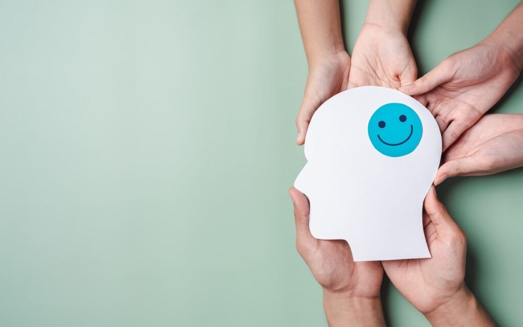 saude_mental Um simbolo sorrindo com mãos ao seu redor, representando terapia cognitivo comportamental em grupo